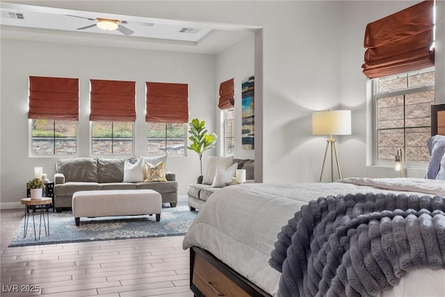 bedroom featuring wood finished floors, visible vents, and multiple windows