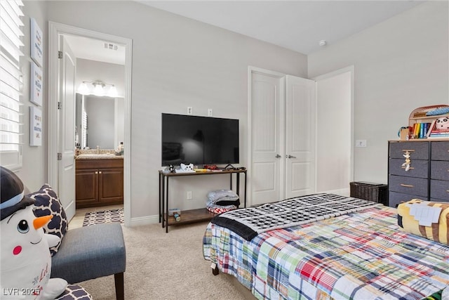 bedroom with visible vents, carpet flooring, ensuite bathroom, and a sink