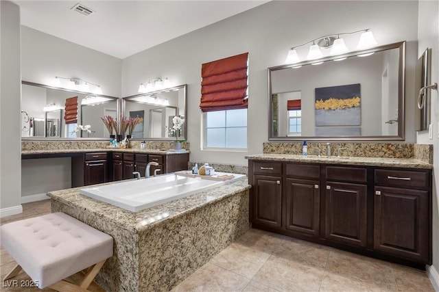 bathroom featuring tile patterned flooring, visible vents, a garden tub, and vanity