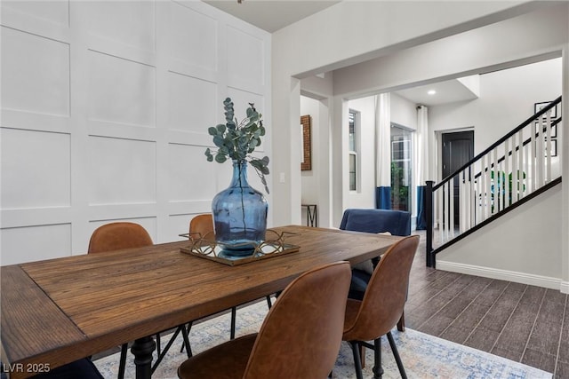 dining space featuring baseboards, wood finished floors, and stairway