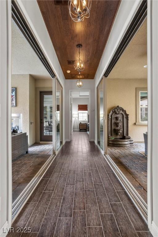 corridor with wooden ceiling, a notable chandelier, and dark wood finished floors