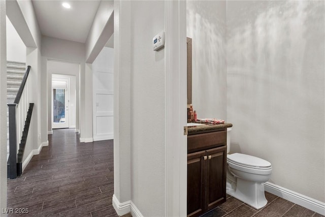 bathroom featuring baseboards, wood finished floors, vanity, and toilet