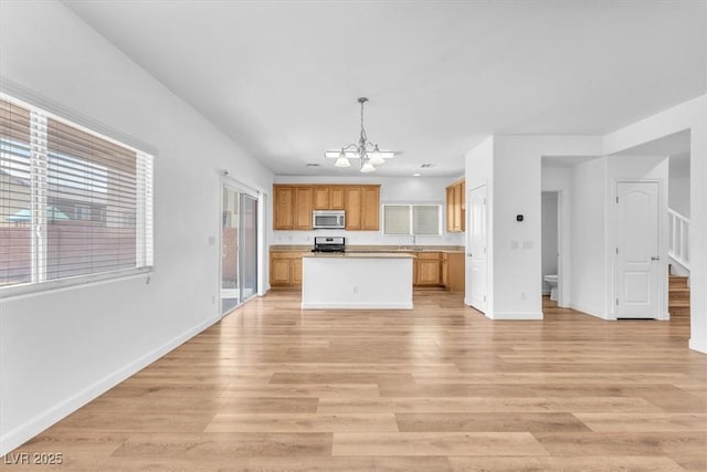 5060 Blue Rose St, North Las Vegas, NV 89081 - kitchen featuring light wood-type flooring, open floor plan, a chandelier, and appliances with stainless steel finishes