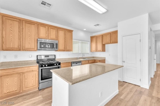 5060 Blue Rose St, North Las Vegas, NV 89081 - kitchen with light wood finished floors, a center island, a sink, light stone countertops, and appliances with stainless steel finishes