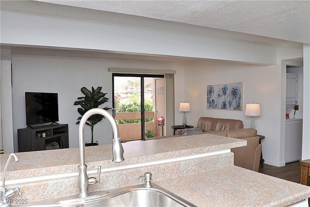 kitchen with wood finished floors, a sink, a textured ceiling, open floor plan, and light countertops
