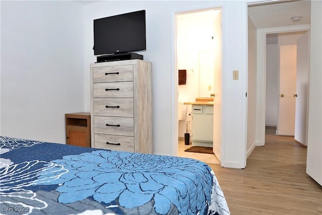 bedroom featuring light wood-type flooring, ensuite bath, and baseboards