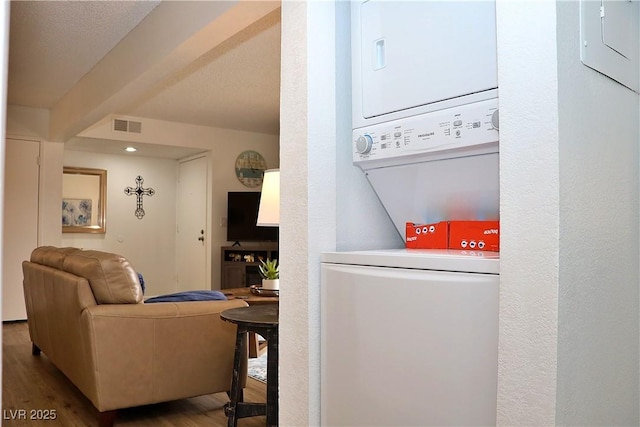 interior space featuring stacked washer and clothes dryer, wood finished floors, and visible vents