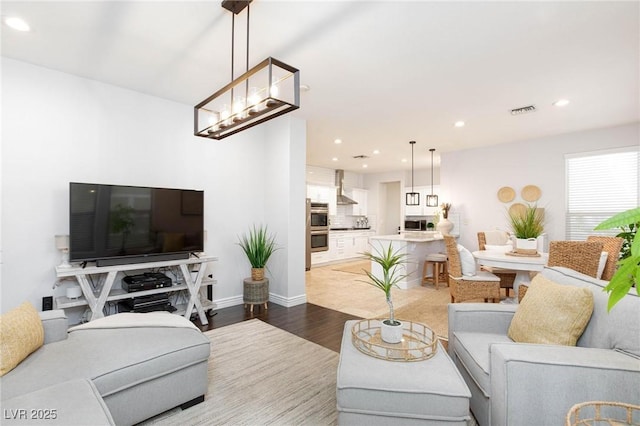 living area with baseboards, wood finished floors, visible vents, and recessed lighting