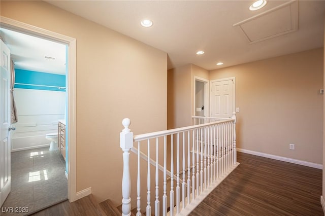 corridor featuring recessed lighting, wood finished floors, baseboards, and an upstairs landing
