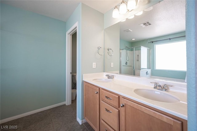 full bath with double vanity, a shower stall, toilet, and a sink