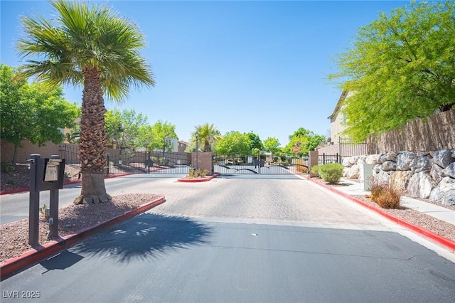 view of road with a gate, a gated entry, and curbs