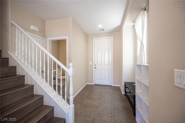 foyer with stairway, baseboards, dark tile patterned floors, visible vents, and recessed lighting