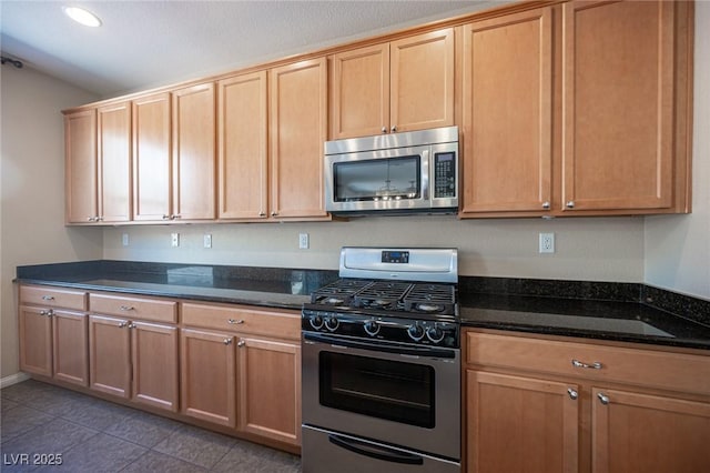 kitchen featuring light brown cabinets, dark stone countertops, light tile patterned floors, appliances with stainless steel finishes, and recessed lighting
