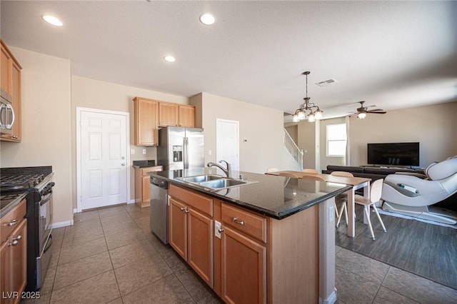 kitchen featuring a sink, dark tile patterned flooring, open floor plan, appliances with stainless steel finishes, and visible vents