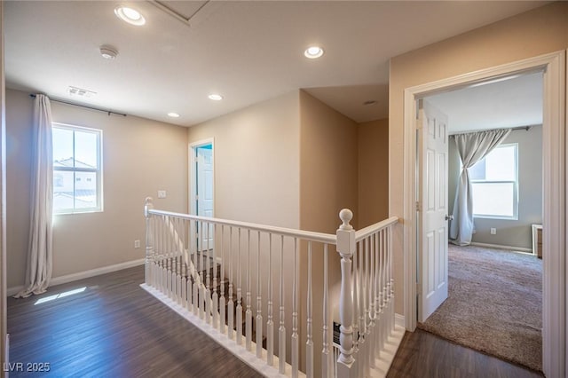 hallway featuring baseboards, visible vents, a healthy amount of sunlight, and an upstairs landing