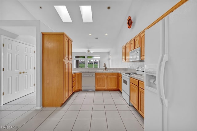 1074 Chaparral Dr, Mesquite, NV 89027 - kitchen with white appliances, a skylight, tile counters, light tile patterned flooring, and vaulted ceiling