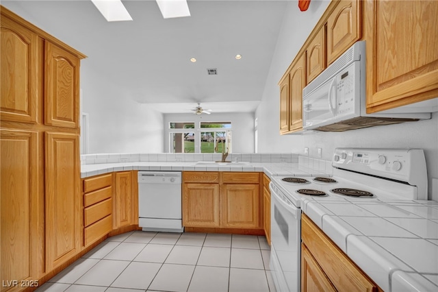 1074 Chaparral Dr, Mesquite, NV 89027 - kitchen with white appliances, a skylight, tile countertops, a ceiling fan, and light tile patterned flooring
