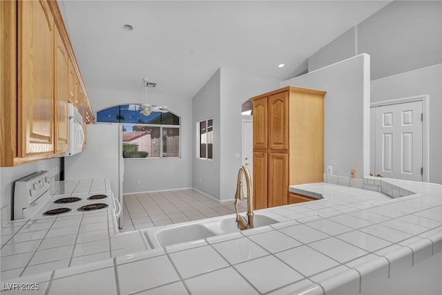 1074 Chaparral Dr, Mesquite, NV 89027 - kitchen with white appliances, tile counters, vaulted ceiling, and light tile patterned floors