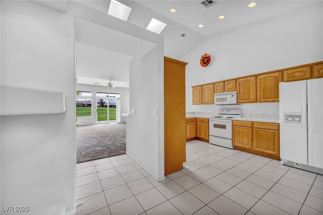 1074 Chaparral Dr, Mesquite, NV 89027 - kitchen featuring white appliances, high vaulted ceiling, a skylight, light carpet, and light tile patterned flooring