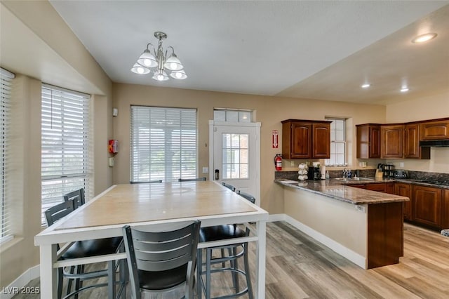 6520 Turtle Hill Rd, Las Vegas, NV 89110 - kitchen featuring a healthy amount of sunlight, baseboards, a notable chandelier, light wood-style floors, and a breakfast bar area