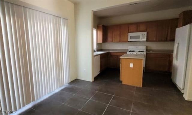 8768 Charm Canyon Ave, Las Vegas, NV 89178 - kitchen with brown cabinets, light countertops, white appliances, dark tile patterned floors, and a kitchen island