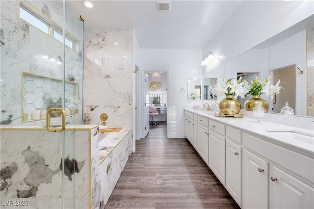 ensuite bathroom with a wealth of natural light, visible vents, a sink, and a marble finish shower