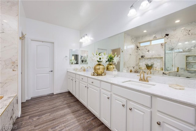 bathroom with double vanity, wood finished floors, a marble finish shower, and a sink