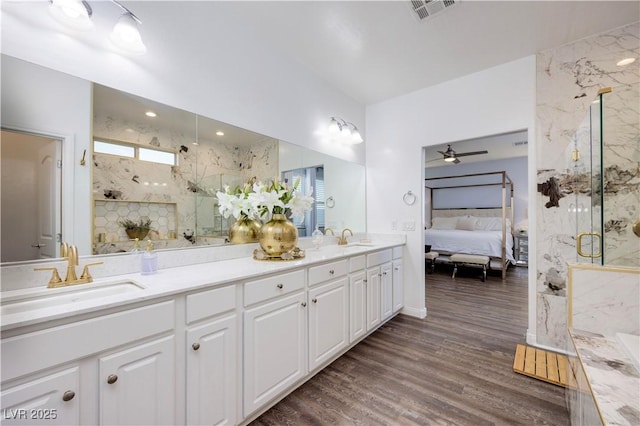 ensuite bathroom featuring a marble finish shower, a sink, visible vents, and double vanity