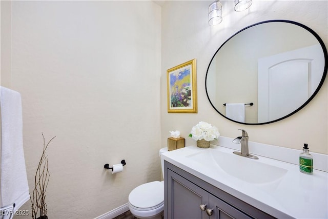 half bath with baseboards, toilet, and vanity