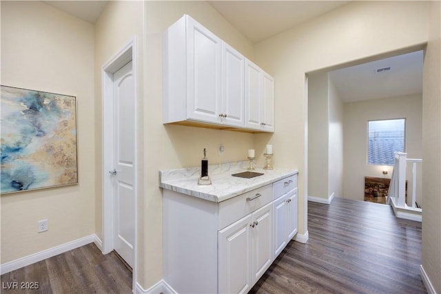 kitchen with white cabinets, baseboards, dark wood-style flooring, and light stone countertops