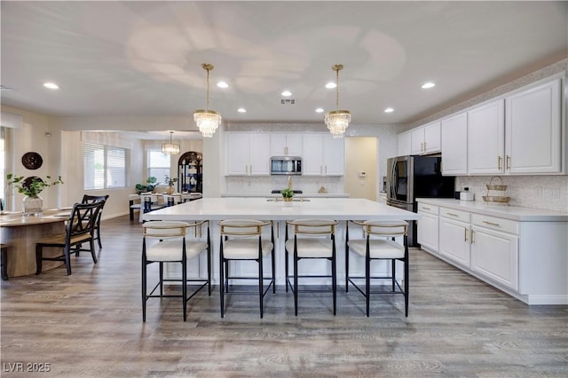 kitchen featuring white cabinets, backsplash, stainless steel microwave, and a breakfast bar area