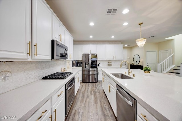 kitchen featuring a sink, light countertops, light wood-style flooring, appliances with stainless steel finishes, and visible vents