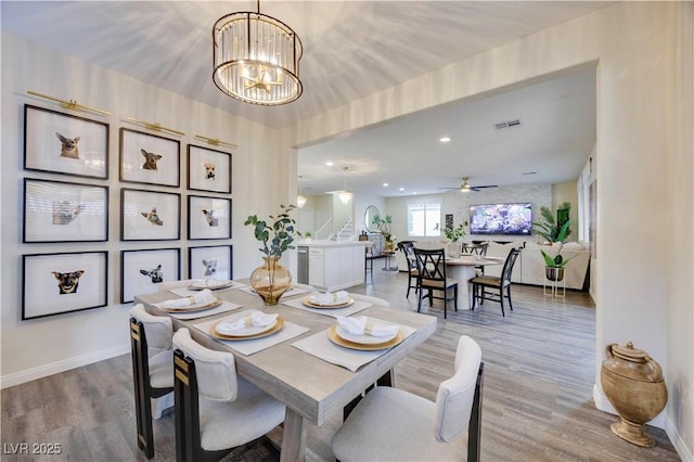 dining area with stairs, a chandelier, light wood-style flooring, baseboards, and visible vents