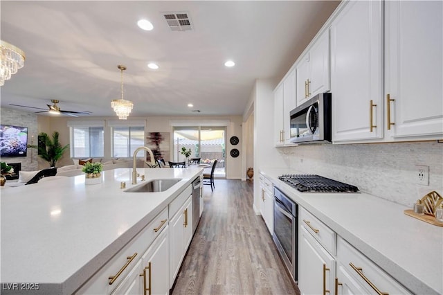 kitchen featuring stainless steel appliances, light countertops, wood finished floors, visible vents, and a sink