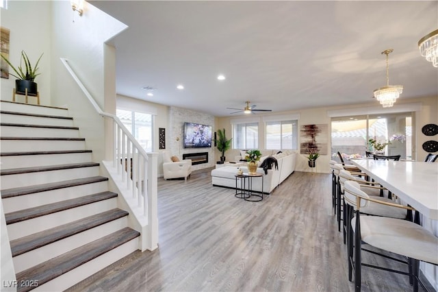 living area featuring stairway, a healthy amount of sunlight, a large fireplace, light wood finished floors, and recessed lighting