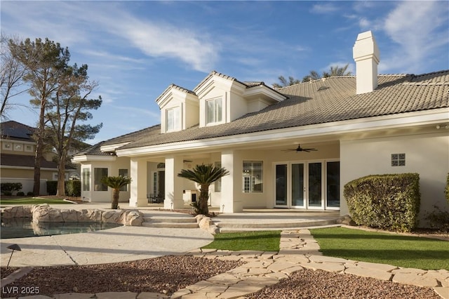 rear view of house with ceiling fan, french doors, a tile roof, and stucco siding