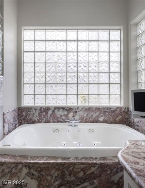 full bathroom with a healthy amount of sunlight and a tub with jets