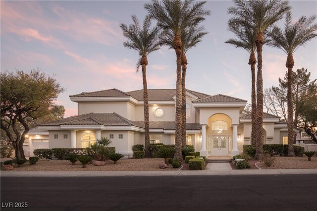 mediterranean / spanish-style home featuring stucco siding, a tile roof, and french doors