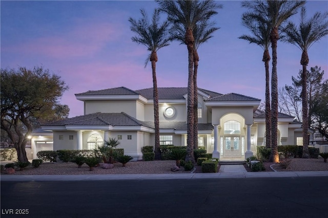 mediterranean / spanish house featuring french doors, a tiled roof, and stucco siding
