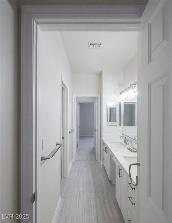 bathroom with baseboards, visible vents, a sink, and double vanity