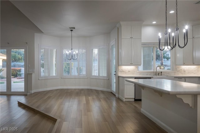 kitchen featuring light countertops, stainless steel dishwasher, a notable chandelier, and a sink