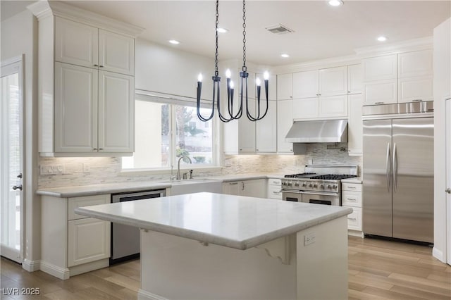 kitchen featuring light wood finished floors, under cabinet range hood, backsplash, visible vents, and appliances with stainless steel finishes