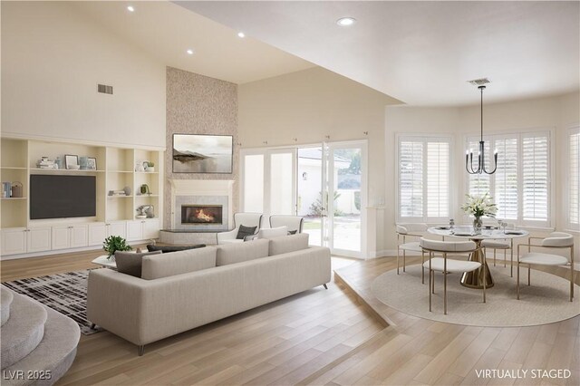living area with high vaulted ceiling, a fireplace, visible vents, and light wood-style flooring