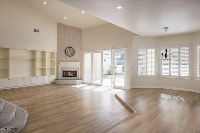 unfurnished living room with baseboards, visible vents, high vaulted ceiling, and a notable chandelier