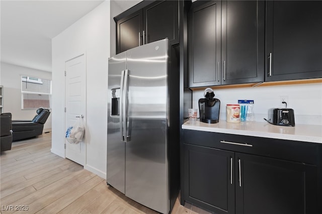 31 Strada Loreto, Henderson, NV 89011 - kitchen with stainless steel fridge with ice dispenser, light countertops, dark cabinetry, light wood-style flooring, and open floor plan