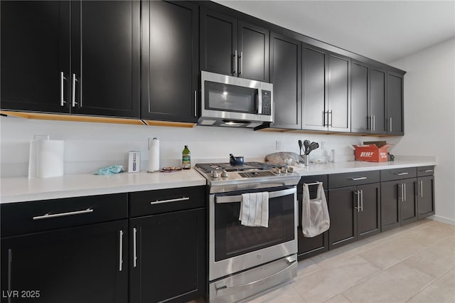 31 Strada Loreto, Henderson, NV 89011 - kitchen with stainless steel appliances, light tile patterned flooring, baseboards, dark cabinetry, and light countertops
