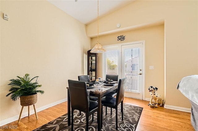dining space featuring vaulted ceiling, baseboards, and wood finished floors