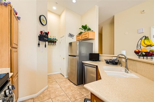 kitchen featuring a sink, light countertops, light tile patterned floors, baseboards, and appliances with stainless steel finishes