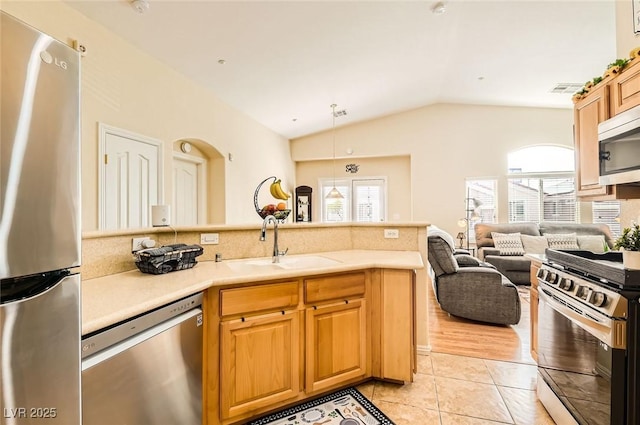 kitchen featuring lofted ceiling, stainless steel appliances, light tile patterned floors, a sink, and light countertops