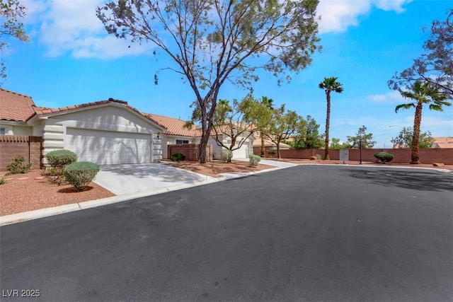 view of front of home with an attached garage, concrete driveway, and fence